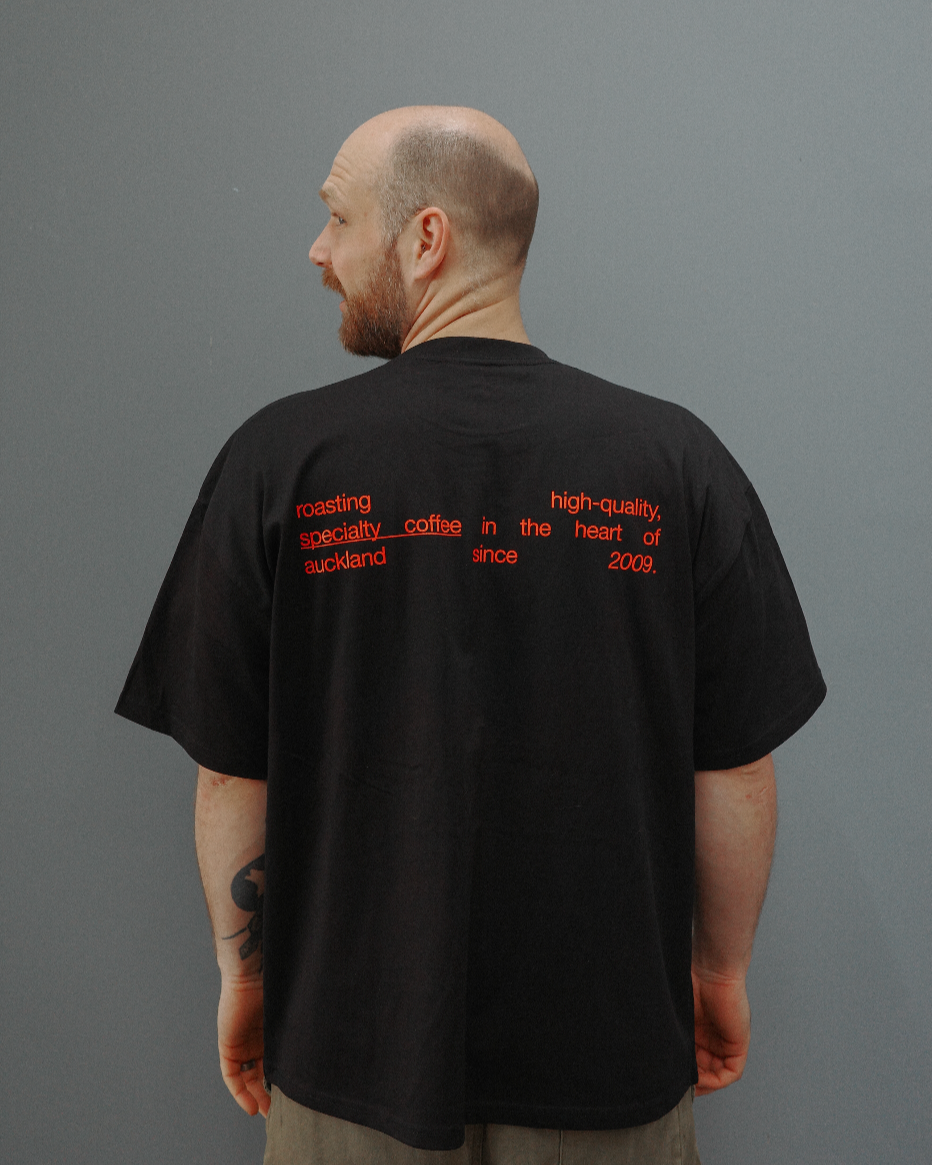 Person wearing a black t-shirt with red text on the back against a gray background