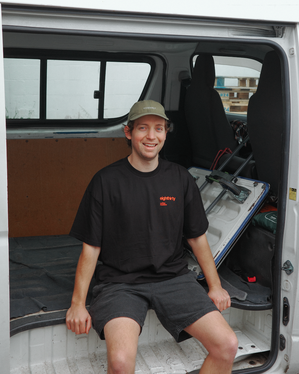 Man sitting inside a van with an open door, smiling.