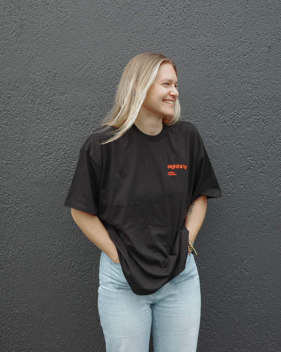 Person wearing a black t-shirt with red text against a gray wall