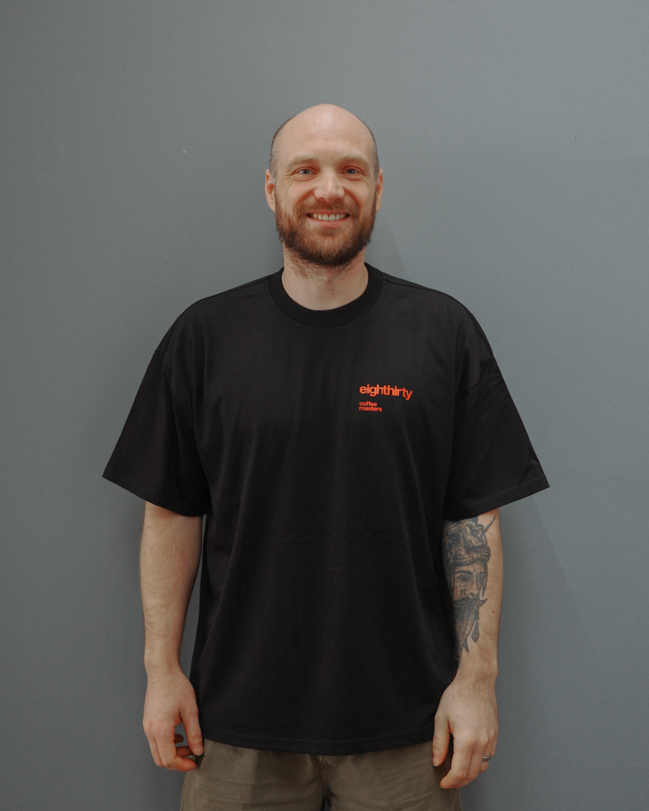 Man wearing a black t-shirt with a logo against a gray background
